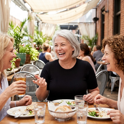 Three women laughing over lunch on a garden terrace