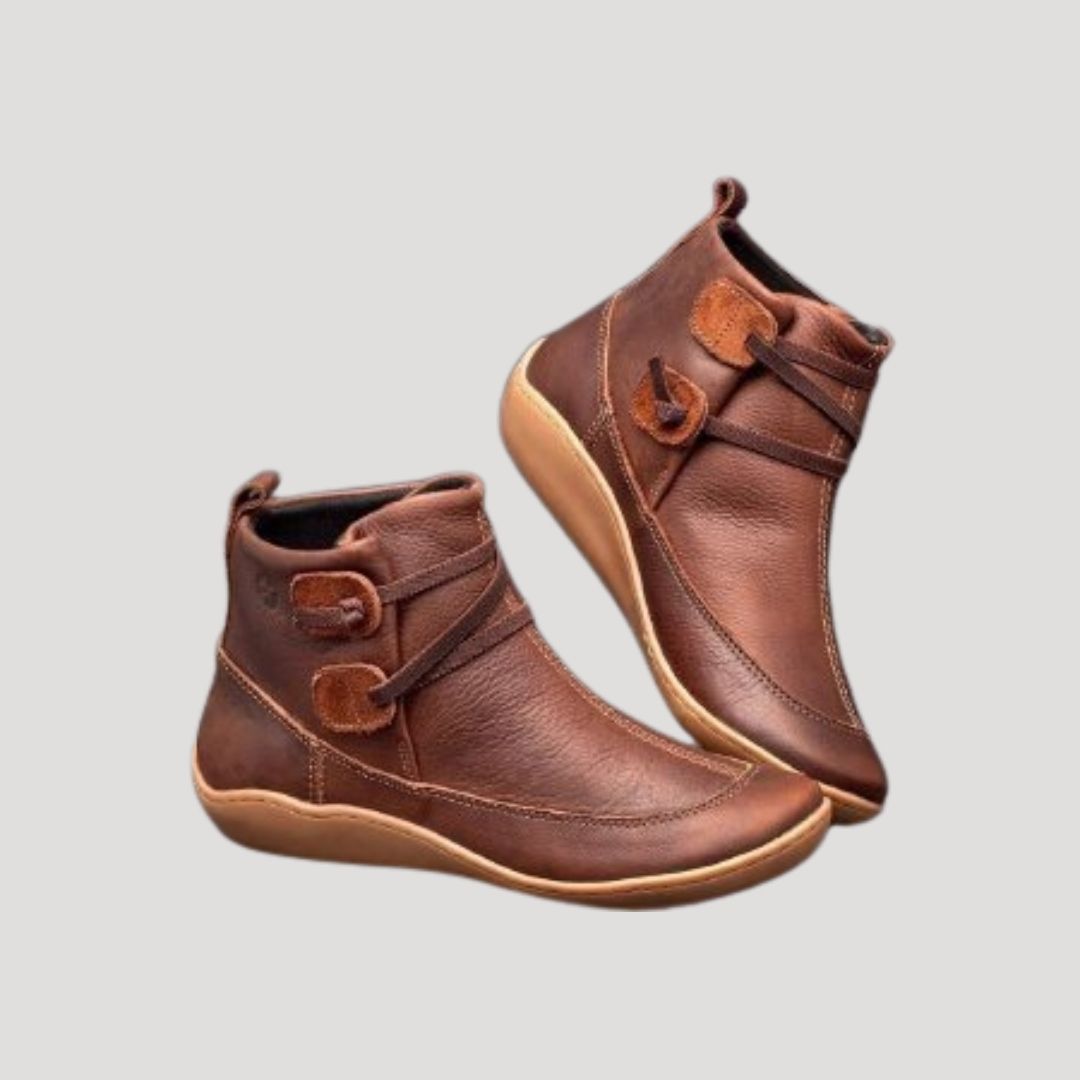 Pair of brown ankle boots with wrapped strap and tab detail on a light background