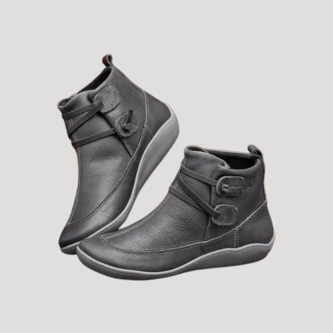 Pair of grey ankle boots with wrapped strap and curved sole